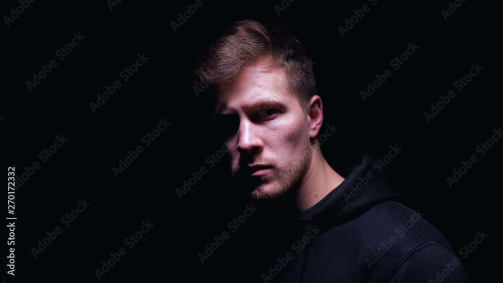 Scared bruised man standing against dark background, victim of hooligan, closeup Scared bruised man standing against dark background, victim of hooligan, closeup