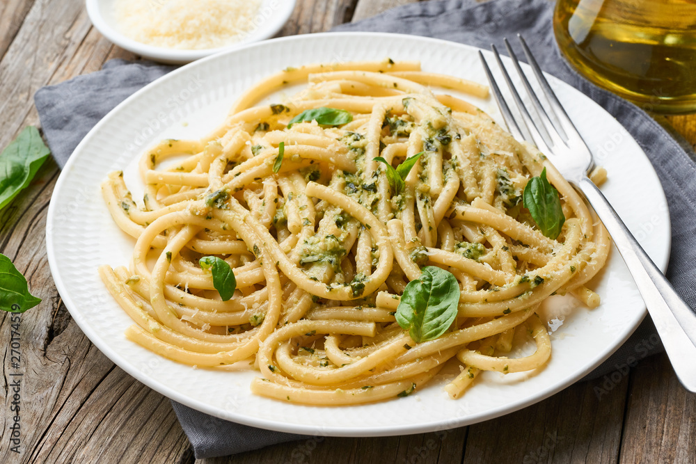 Pesto spaghetti pasta with basil, garlic, pine nuts, olive oil. Rustic table, side view Pesto spaghetti pasta with basil, garlic, pine nuts, olive oil. Rustic table, side view