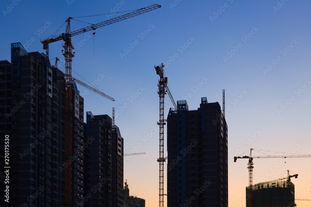 Construction site with many cranes at sunset Construction site with many cranes at sunset