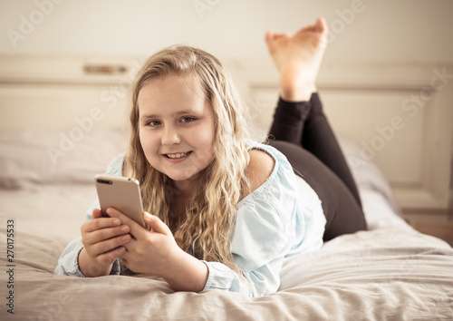 Happy cute kid playing games and watching videos on social media on mobile phone