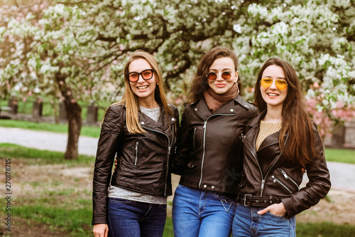 Best friends girls having fun, joy. Lifestyle. Beautiful young women in sunglasses dressed in the nice clothes smiling on a sunny day. photos of girls against the background of flowering trees