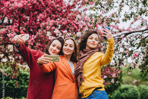 The best friends. Selfie - Three beautiful woman. Lifestyle. Beautiful young women in sunglasses dressed in the bright clothes smiling. girls make photo of against the background of flowering trees