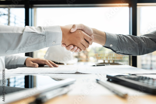 Architect and engineer construction workers shaking hands while working for teamwork and cooperation concept after finish an agreement in the office construction site, success collaboration concept