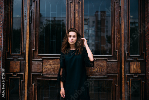 Young girl in green dress near old big building door photo