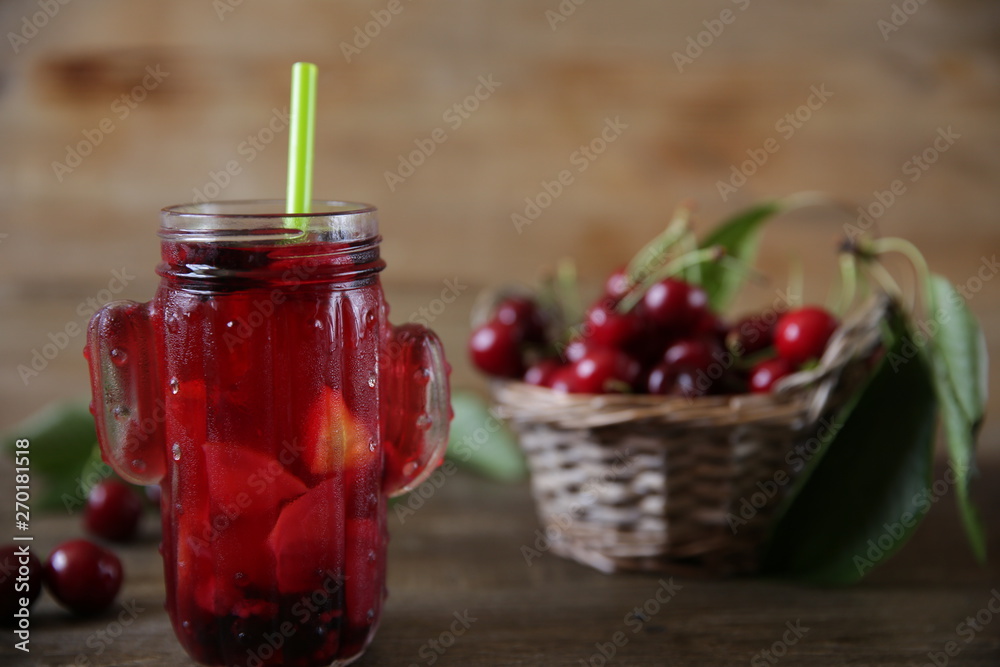 Berries and citrus infused water cocktail, compote, lemonade or tea. Summer iced cold drink with berries, cherry, lemon on a wooden rustic background with branch of cherry. With copy space for text. Berries and citrus infused water cocktail, compote, lemonade or tea. Summer iced cold drink with berries, cherry, lemon on a wooden rustic background with branch of cherry. With copy space for text.