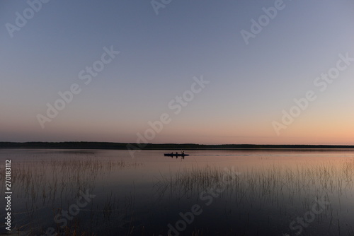     yaking people  on the calm water of the lake in the sunset light return from a hike