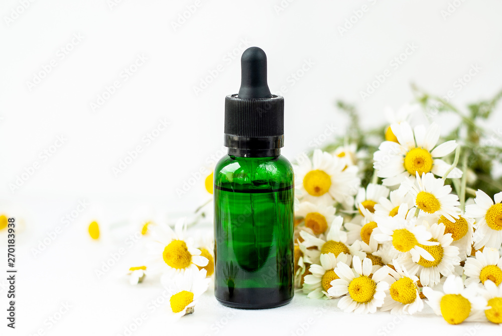 Essential aroma oil with camomile on white background. Essential aroma oil with camomile on white background.