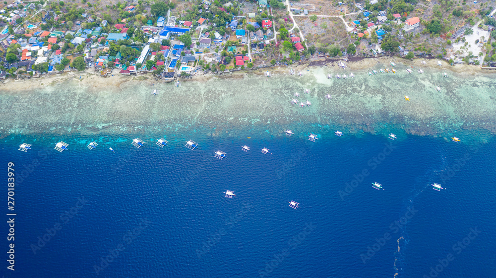Aerial view of Filipino boats floating on top of clear blue waters, Moalboal is a deep clean blue ocean and has many local Filipino boats in the sea. Moalboal, Cebu, Philippines.