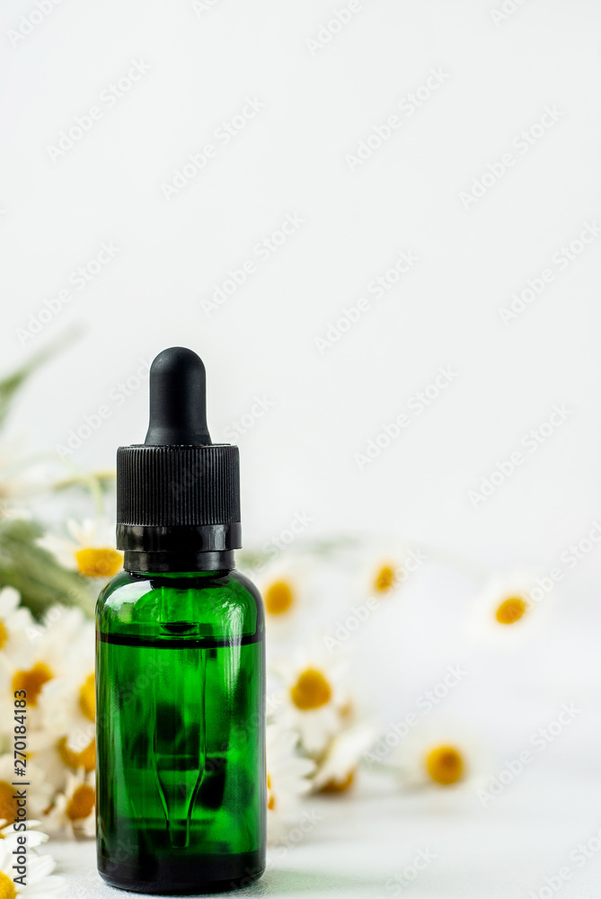 Essential aroma oil with camomile on white background. Essential aroma oil with camomile on white background.
