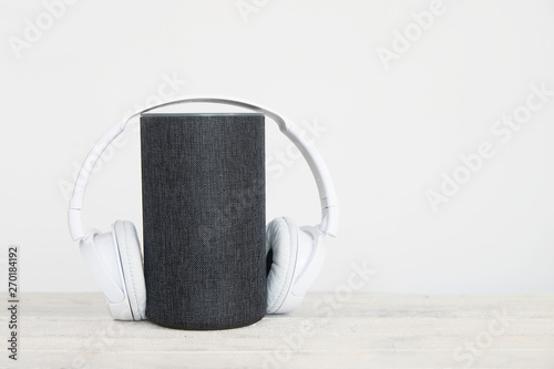 Smart speaker device and hearphones on the left against a white background. Empty copy space for Editor's text photo