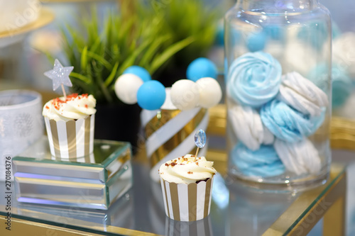 Anniversary/wedding delicious sweet dessert at blue and white tones - cupcakes, marshmallow, vanilla cake pops. Stylish sweet table.