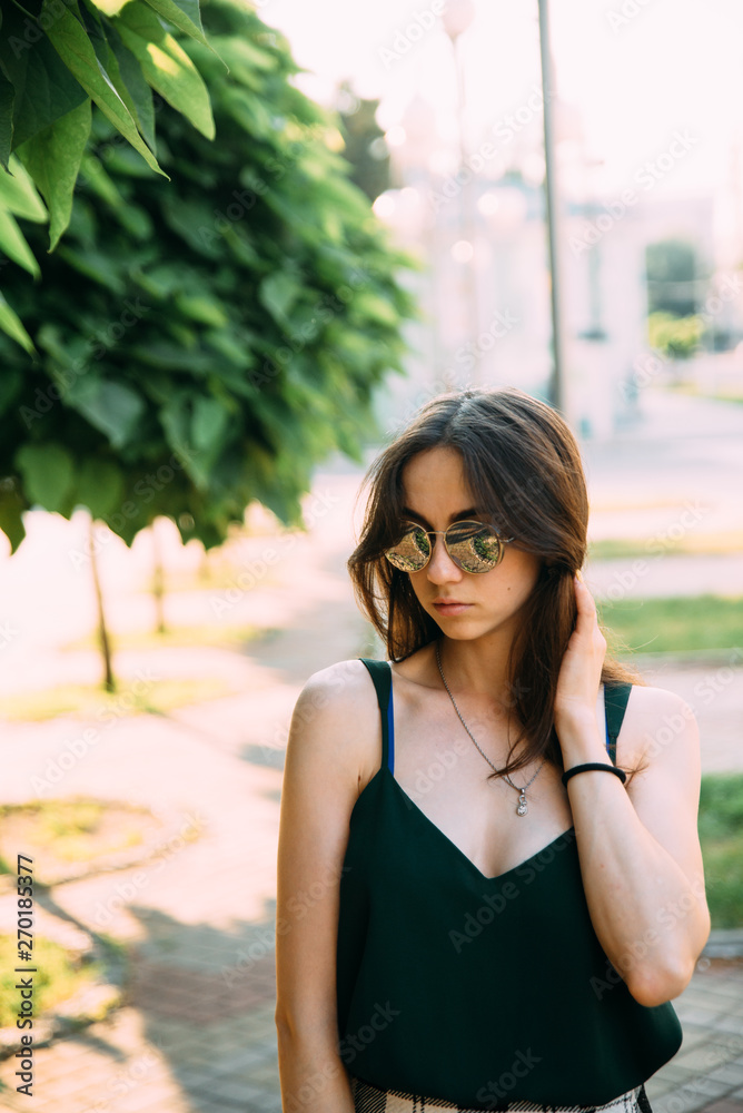 Brunette girl in a summer day in the city wearing round sunglasses Brunette girl in a summer day in the city wearing round sunglasses