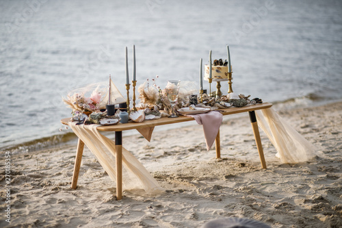 Sea wedding decor on the coast. Wedding cake and flowers at the event.