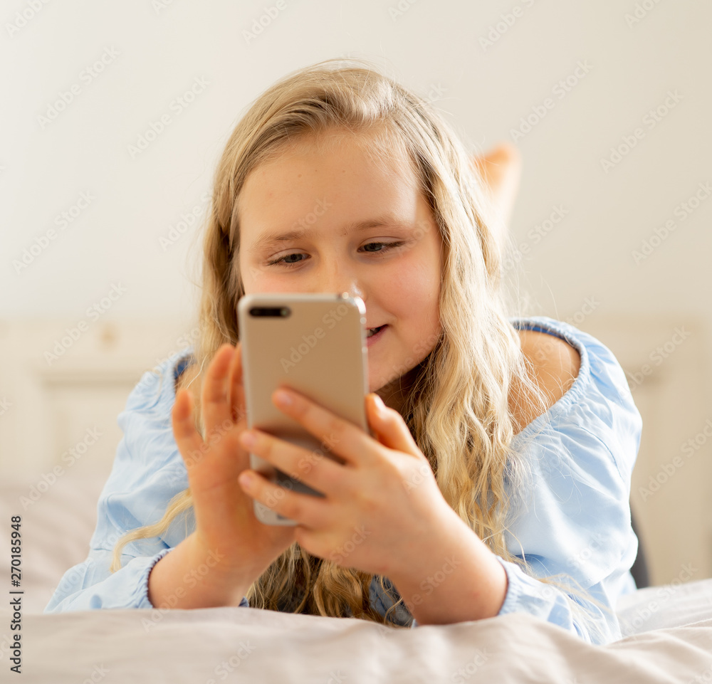 Happy cute kid playing games and watching videos on social media on mobile phone Happy cute kid playing games and watching videos on social media on mobile phone