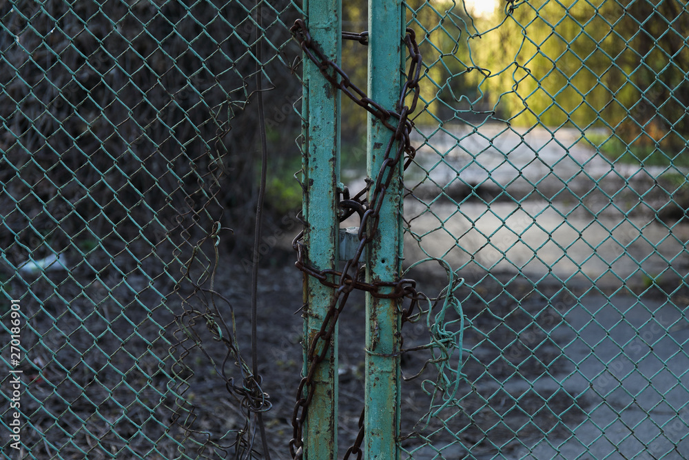 Closed lock with a chain on an old metal fence