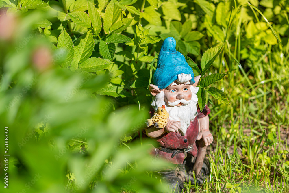 The figure of a garden gnome in the green grass. Copy space. Selective focus.