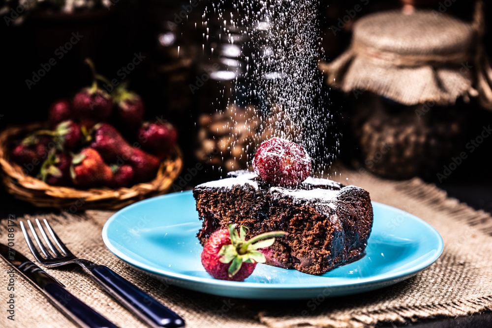 A slice of brownie with strawberries on a blue plate. Sugar snow. A slice of brownie with strawberries on a blue plate. Sugar snow.