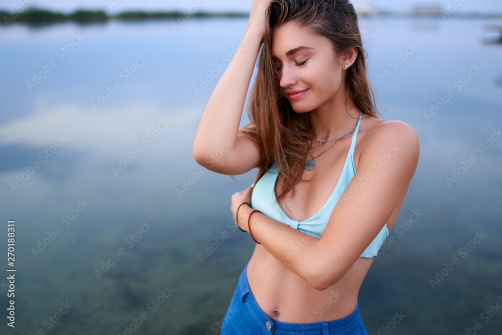 Beautiful lady on tropical island beach with flat mirror glassy water  surface. Fashionable tanned woman with