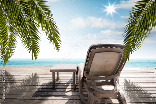 Wooden pier of free space for your decoration and summer chair. Free space for your decoration and green leaves of palms. 