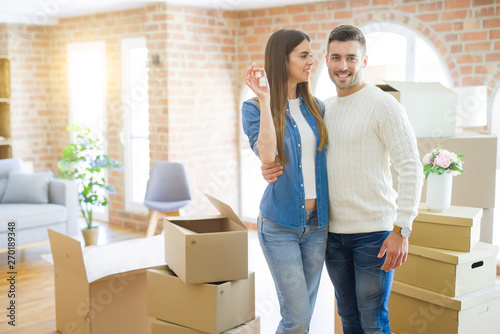 Young couple moving to a new home, hugging in love showing keys of new apartment smiling very happy © Krakenimages.com