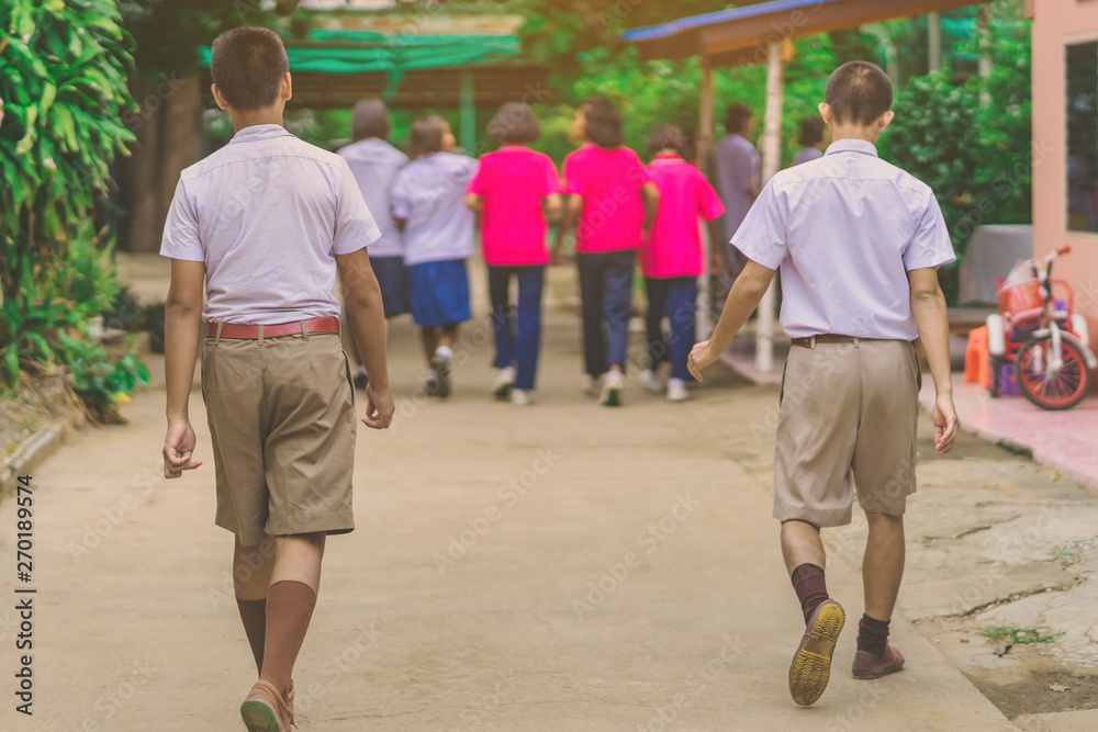 Happiness male students walk behind his girlfriends in school. Happiness male students walk behind his girlfriends in school.