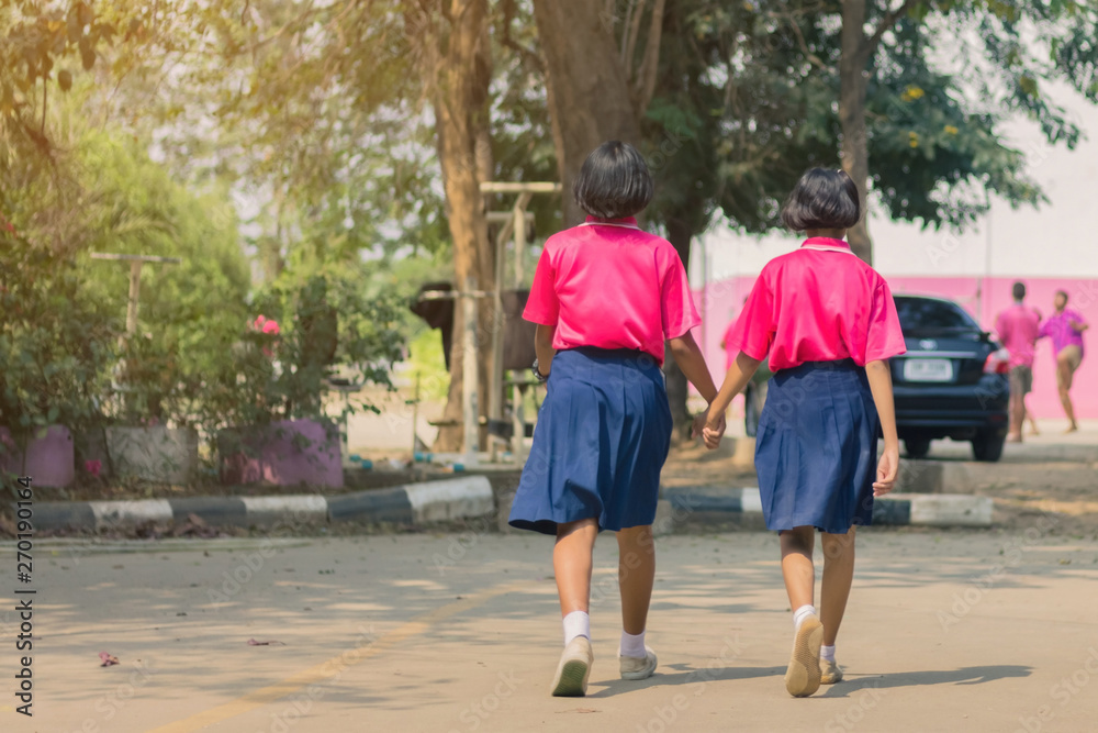 Back view of happiness primary girl students in pink shirt and blue skirt walk to classrooms with their friends. Back view of happiness primary girl students in pink shirt and blue skirt walk to classrooms with their friends.