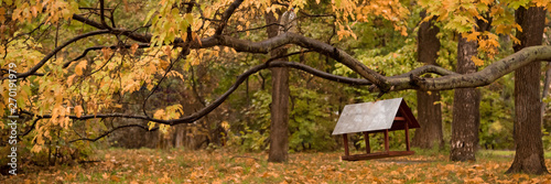 Canvas Print Bird feeder on a tree branch in autumn park