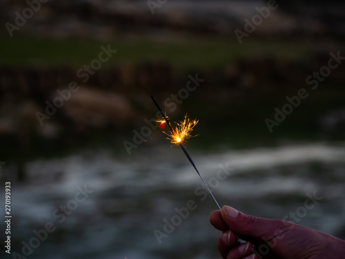 An unrecognizable person with a sparkler sizzling in his hand