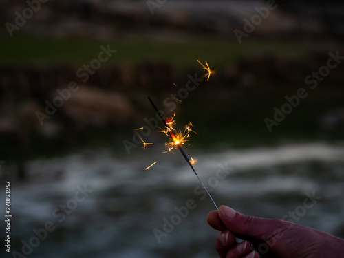 An unrecognizable person with a sparkler sizzling in his hand