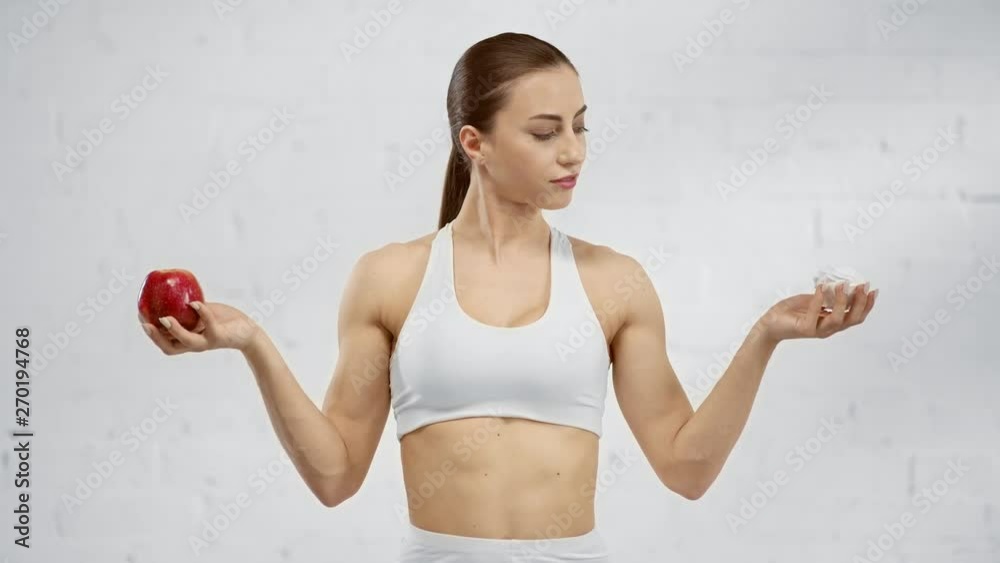 hesitated woman holding read apple with marshamallow and choosing marshmallow hesitated woman holding read apple with marshamallow and choosing marshmallow