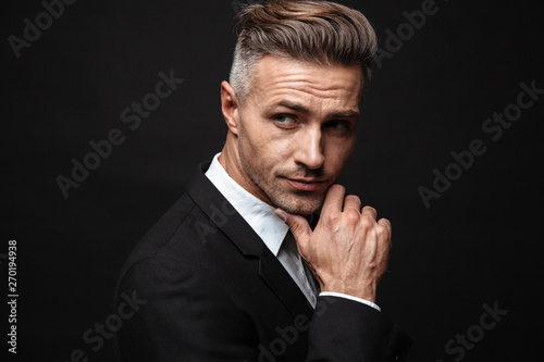 Handsome mature business man posing isolated over black wall background.