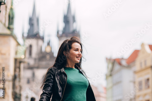 Street portrait of adorable brunette woman with long hair posing at Old Town Square in Prague. smiling pretty brunette girl, lifestyle. observatory of astronomical clock tower in Prague, Czech