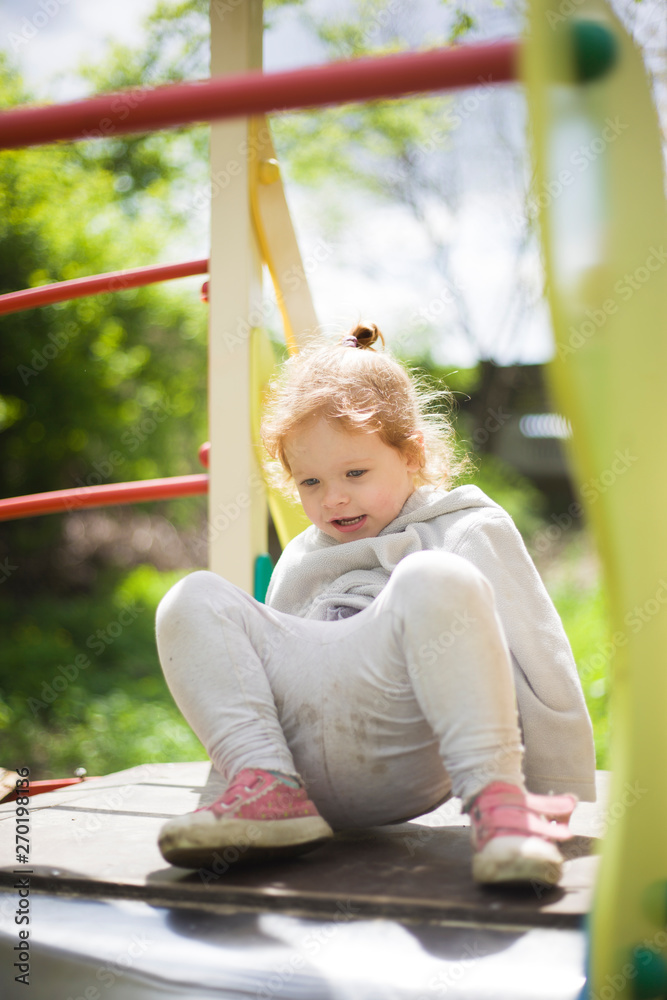 the little girl climbed onto a children slide on a playground for children and is very happy to play the little girl climbed onto a children slide on a playground for children and is very happy to play