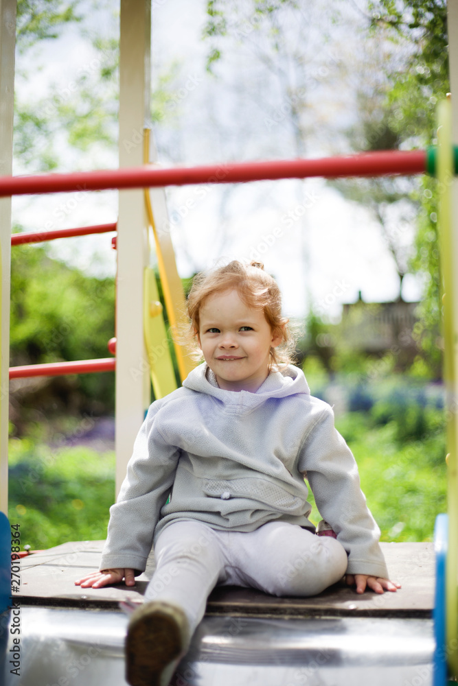 the little girl climbed onto a children slide on a playground for children and is very happy to play the little girl climbed onto a children slide on a playground for children and is very happy to play