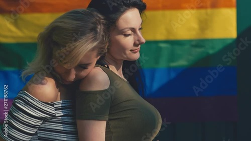 Young lesbian LGBT couple on a background of the rainbow flag. LGBT rights, lesbian family