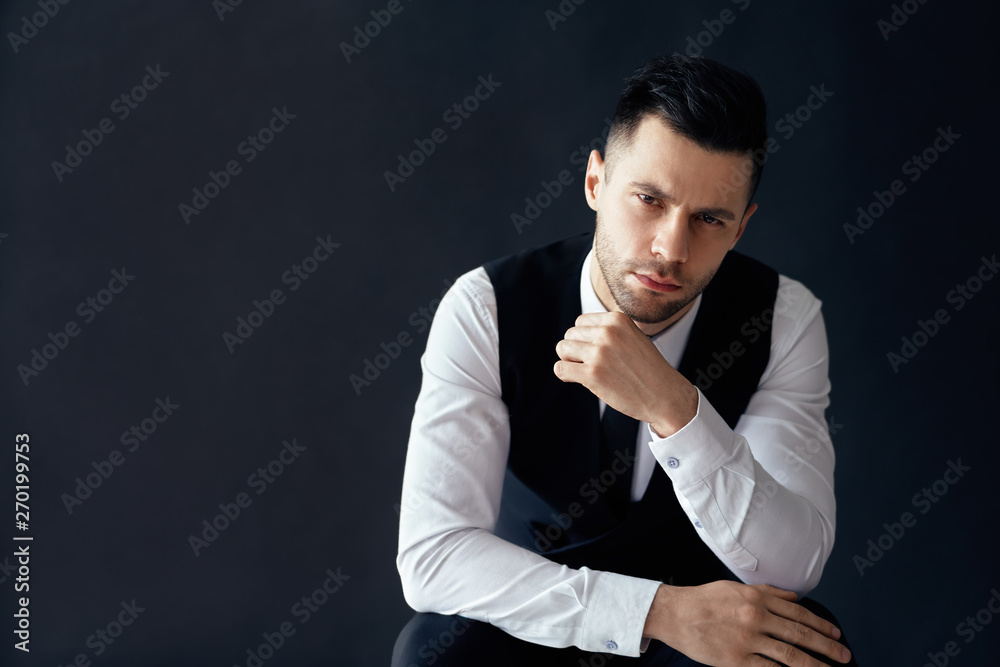 Handsome thoughtful man portrait in suit on dark background