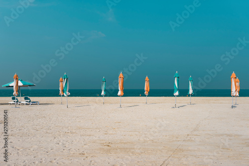 Sandy beach with closed umbrellas against the backdrop of azure water photo