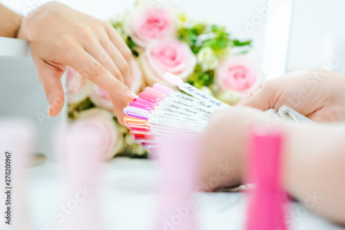 Frau bei der Maniküre sucht sich eine Farbe für die Nägel aus photo