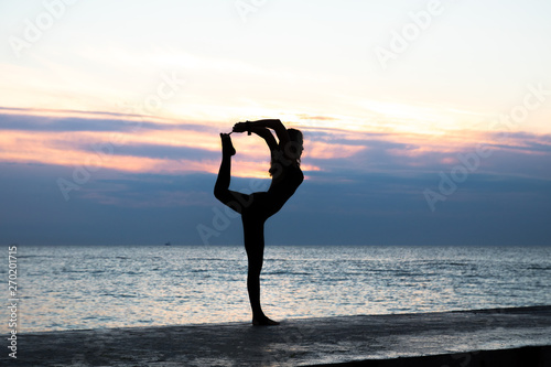 unrecognizable senoir woman with beautiful body profissiionally doing yoga at sunrise on the sea, silhouette of yoga poses photo