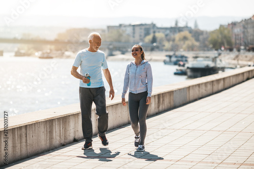 Fit senior man in good shape jogging and exercising together with his young adult daughter coach or instructor.