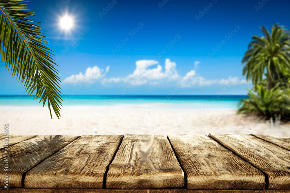 Wooden table background of free space and summer landscape of beach with palms and ocean. Wooden table background of free space and summer landscape of beach with palms and ocean.
