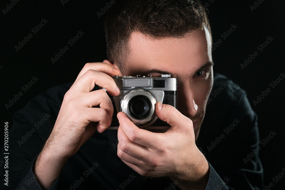 Man photographer holding a retro photo camera. Shooting process. Photographer looks at viewfinder. Man photographer holding a retro photo camera. Shooting process. Photographer looks at viewfinder.