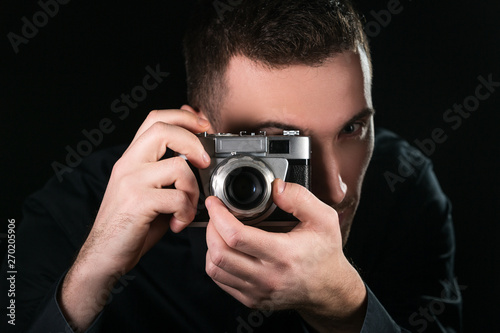 Man photographer holding a retro photo camera. Shooting process. Photographer looks at viewfinder.