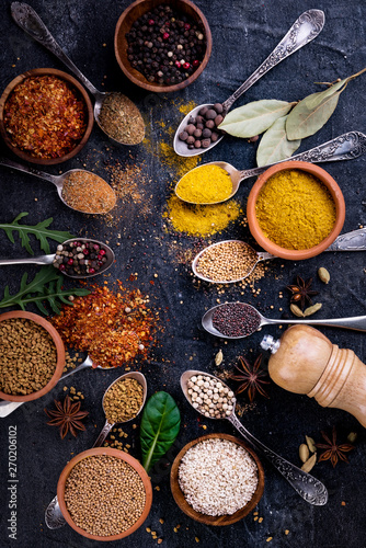 Spices and herbs on black background, top view. Indian cuisine.