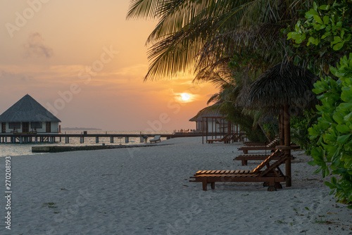 Fototapeta Naklejka Na Ścianę i Meble -  wooden beach lounger with palmes during sunset