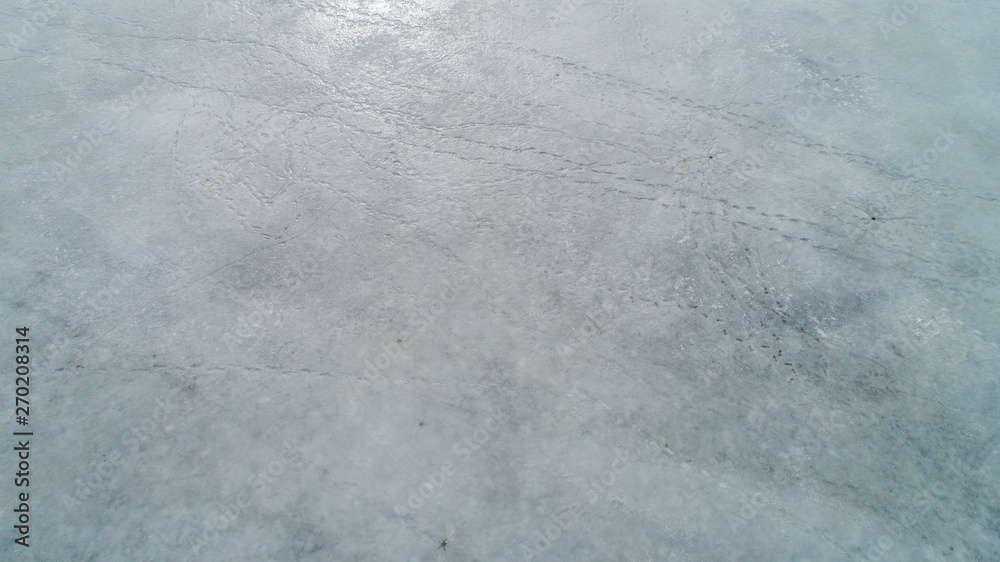 Naklejka premium ice surface on the water in the spring with traces of fishermen and people