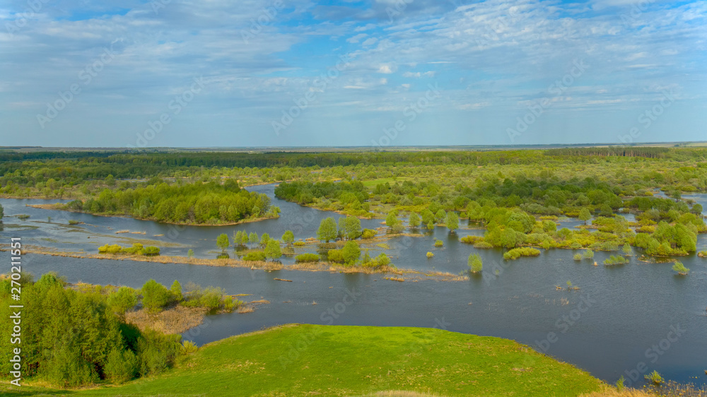 Horizontal landscape: the river flooded the valley. River and the field on a sunny summer day. Voroninsky National Park, Tambov Oblast, Russia.