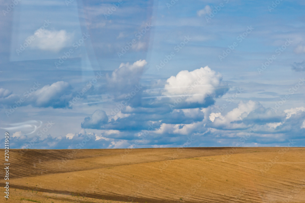 brown plowed non-seeded field on a background of blue summer sky. sunny sky over an empty meadow. serenity, bliss. desktop wallpaper brown plowed non-seeded field on a background of blue summer sky. sunny sky over an empty meadow. serenity, bliss. desktop wallpaper