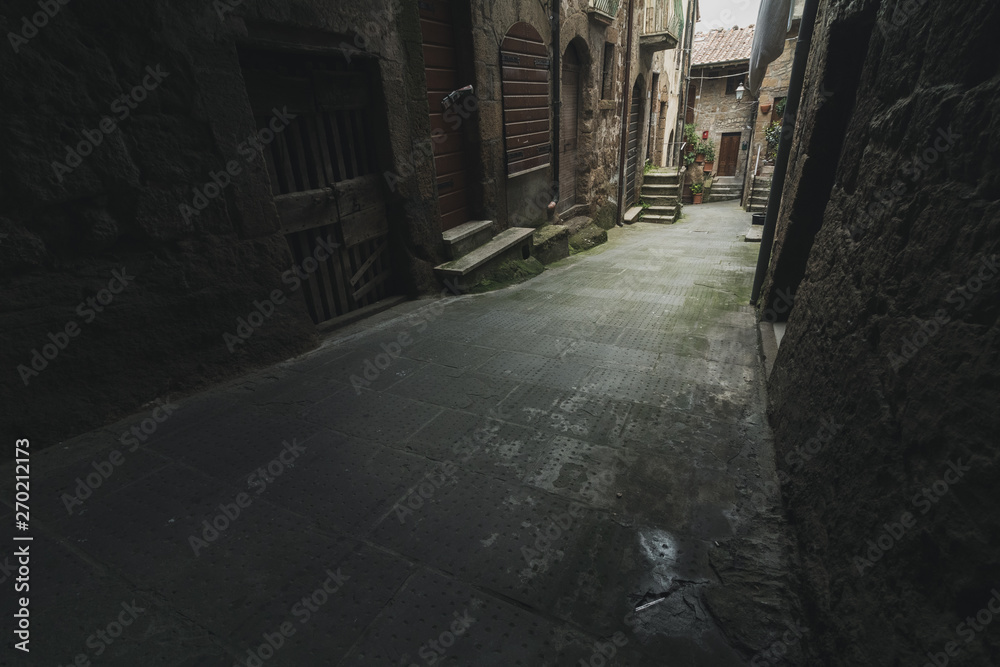 Dark alley in old medieval town in Italy. Light in the distance of the narrow street