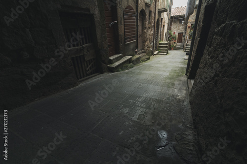 Dark alley in old medieval town in Italy. Light in the distance of the narrow street
